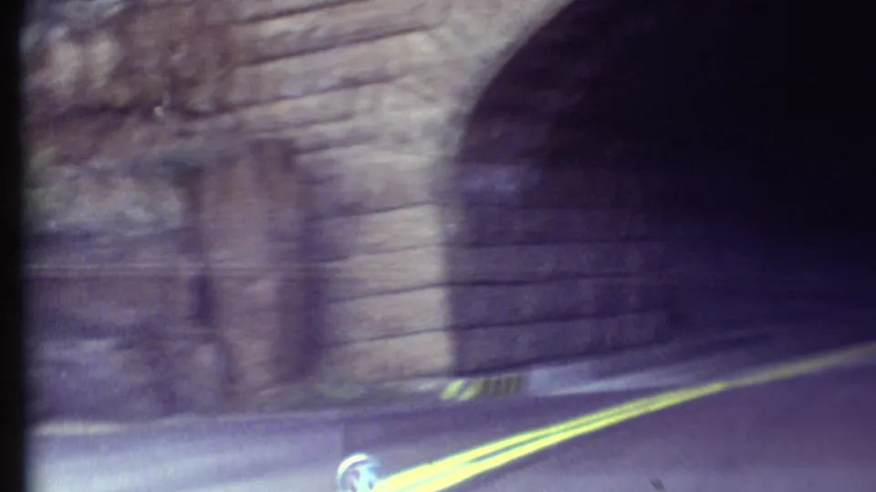 1972 Grand Canyon 8mm frame from inside the tunnel entrance, with masonry walls and blurred road lines.