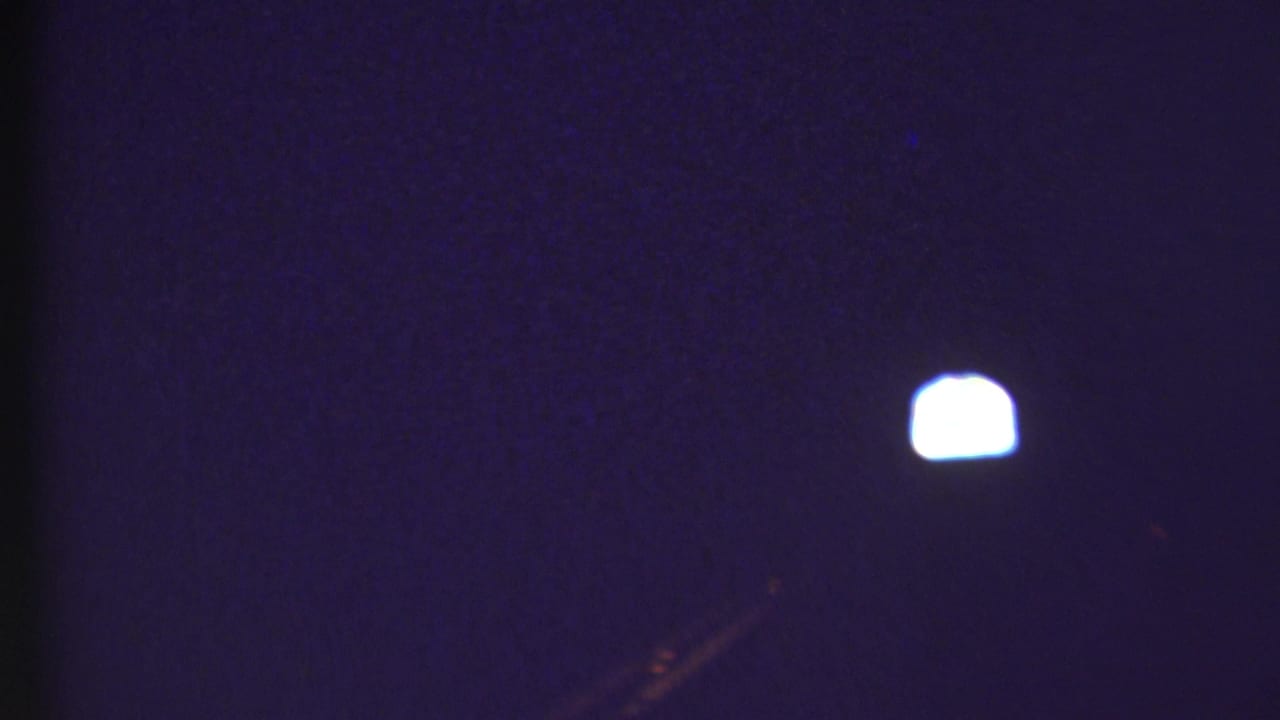 Dark, blue-toned 8mm frame from the 1972 Grand Canyon travel clip with a small bright light and little surrounding detail.