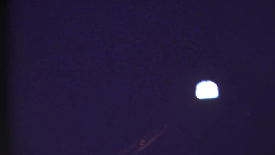 Dark, blue-toned 8mm frame from the 1972 Grand Canyon travel clip with a small bright light and little surrounding detail.