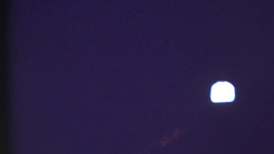 Dark 8mm frame from the 1972 Grand Canyon travel footage, showing a small bright light against a blue-purple exposure.