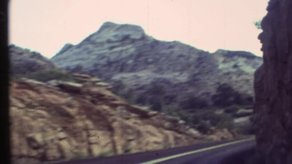 Passenger-shot 1972 view of a large rocky hillside above the Grand Canyon road corridor.