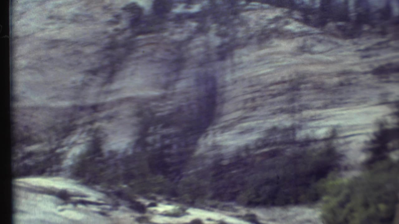 Layered rock face and trees blur past outside a vehicle window.