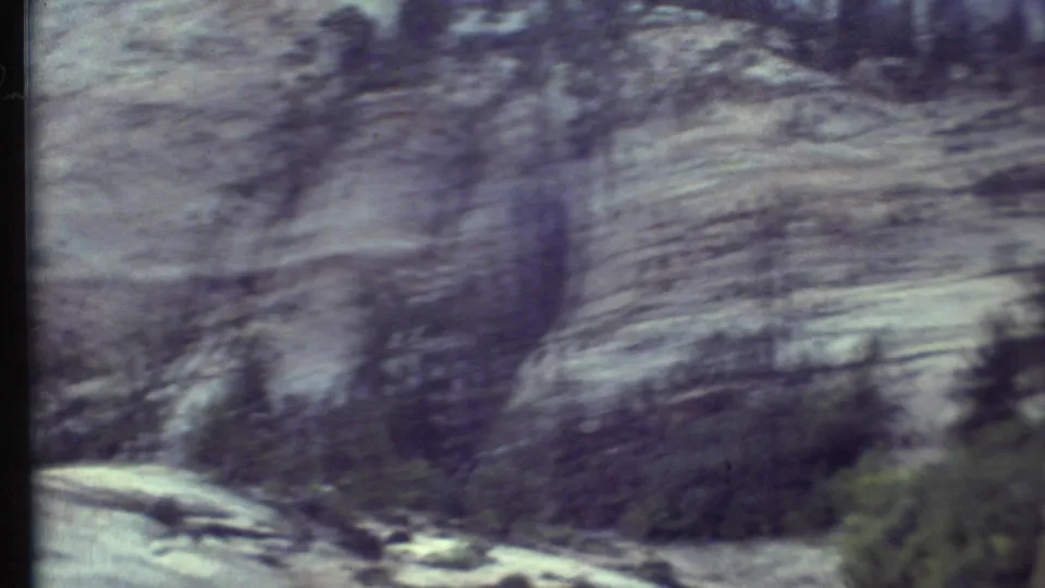 Grand Canyon, Arizona rock layers and evergreen trees appear through motion blur in this 1972 in-car 8mm frame.