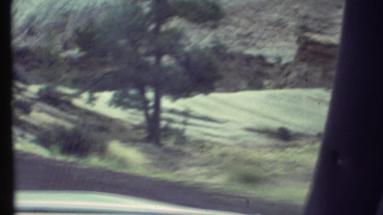 1972 8mm travel footage begins with a blurred view from a moving vehicle, showing arid terrain, pale rock, brush, and a dark window pillar.