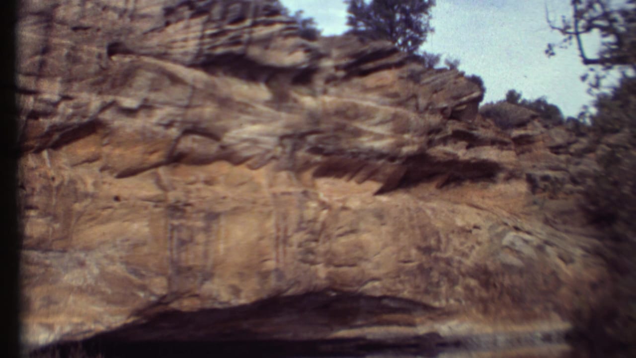 Weathered sandstone ledges and sparse trees appear in a soft, grainy 1972 home-movie view of the desert park landscape.