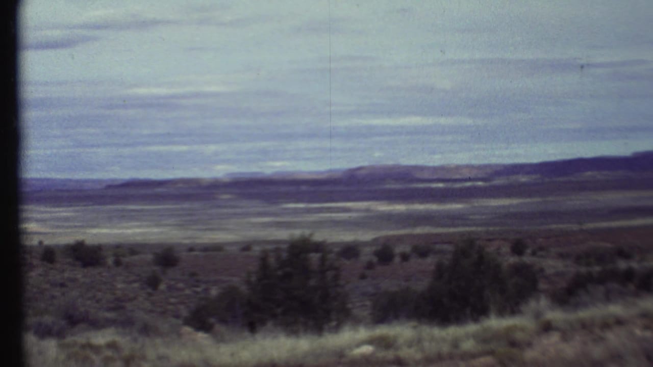 1972 Arizona landscape frame showing a broad desert basin, scattered brush, low ridgelines, and muted 8mm color.