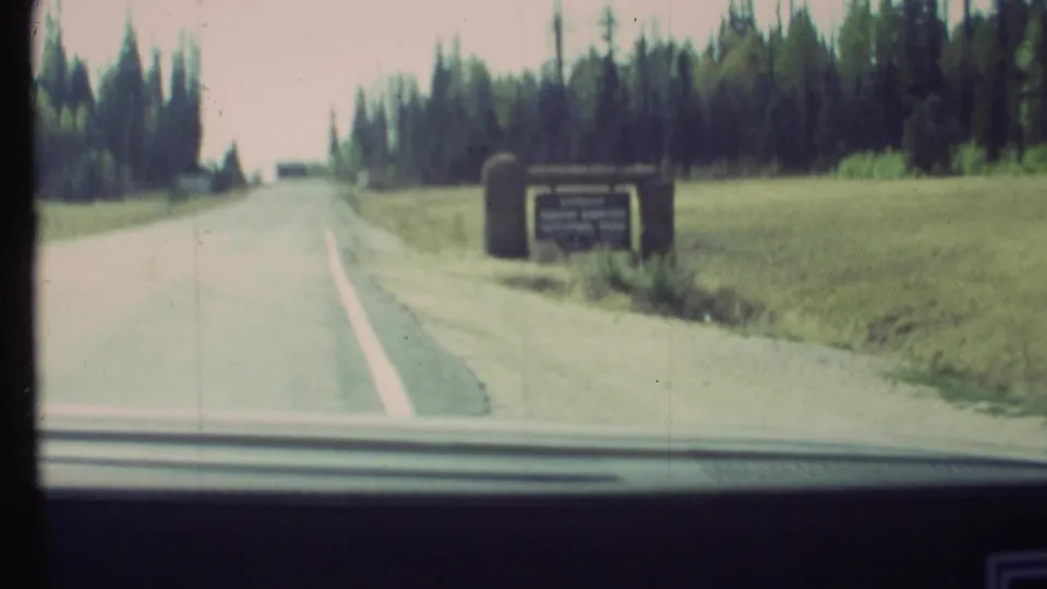Grand Canyon National Park entrance sign passes on the roadside in 1972 home-movie footage from a moving car.