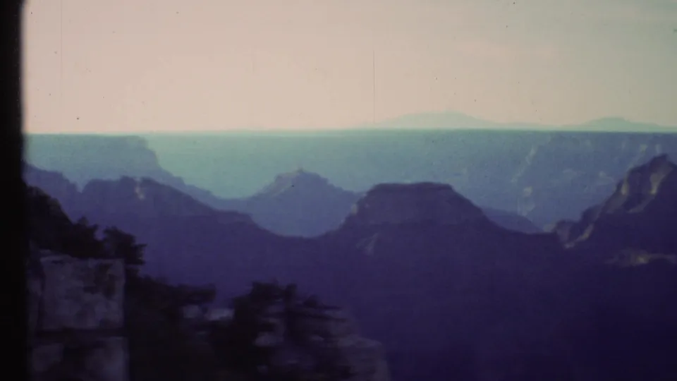 Wide Grand Canyon overlook from a 1972 home movie, showing distant mesas and shadowed canyon walls.