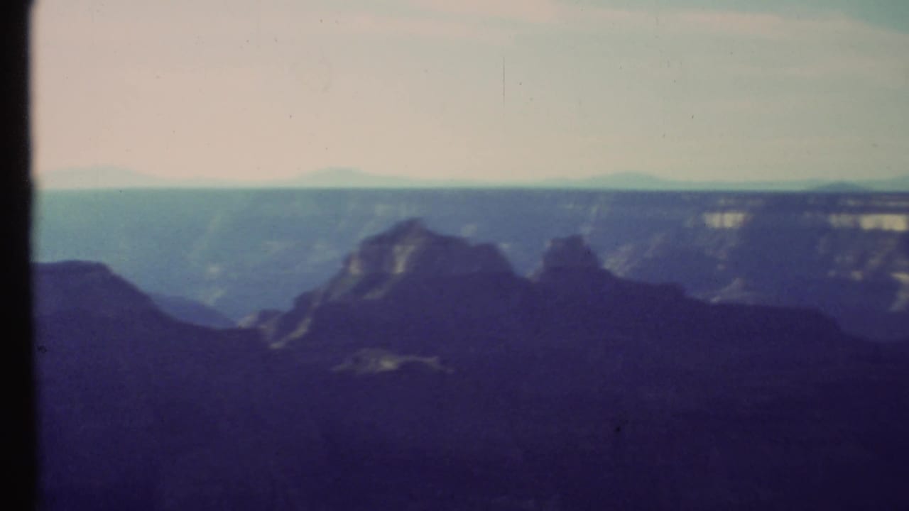 Layered canyon formations and distant horizon seen through a soft film frame.