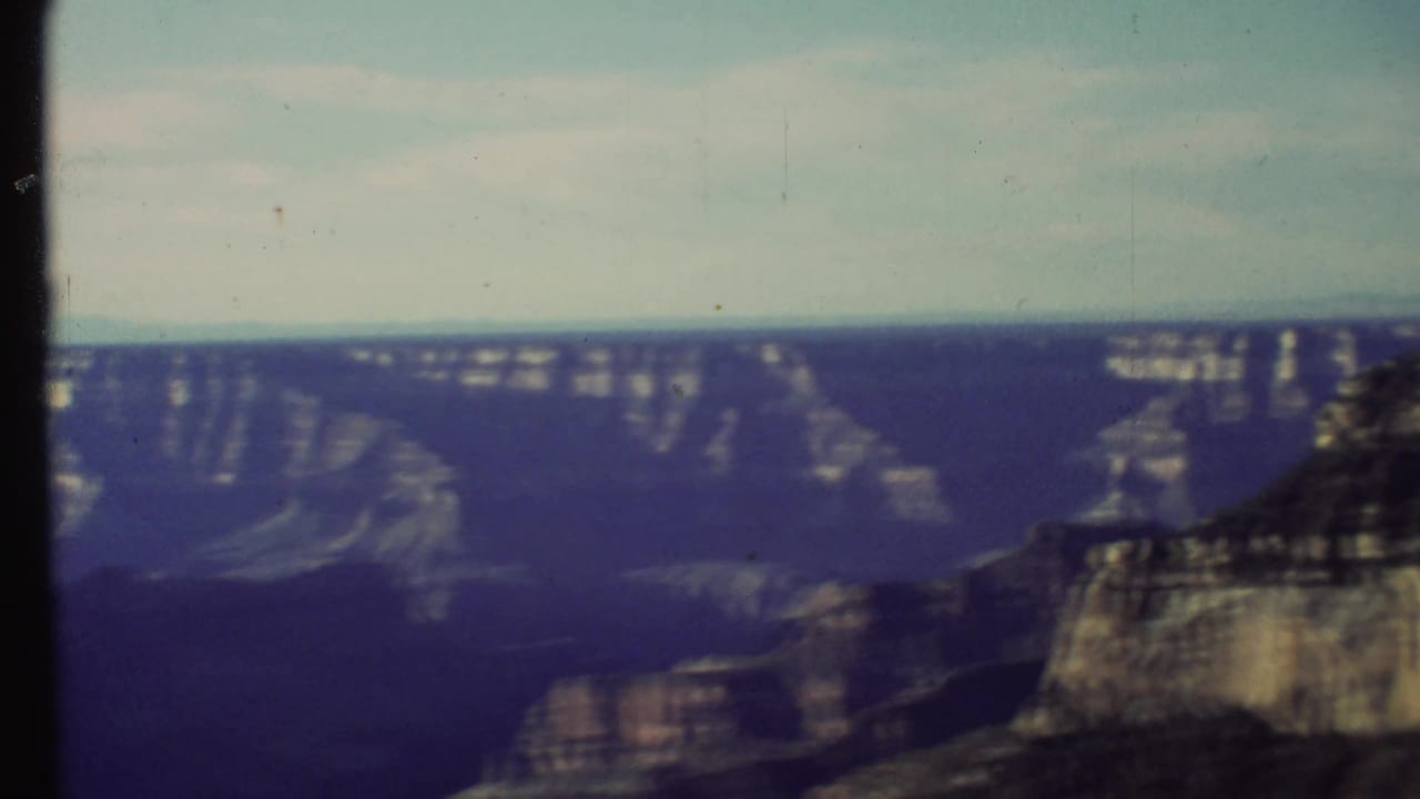 Soft 8mm view across layered Grand Canyon cliffs under a pale sky.