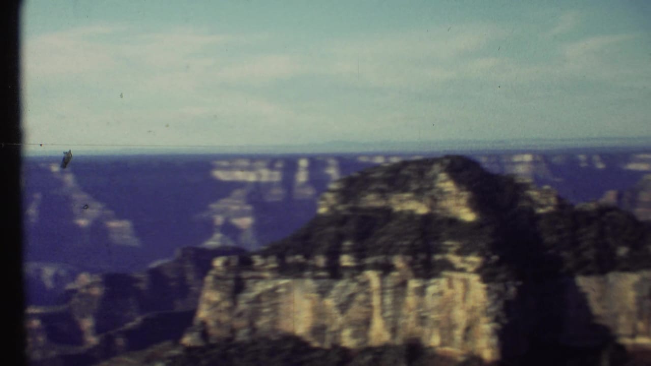 1972 home-movie frame of a prominent Grand Canyon rock formation with distant canyon walls beyond it.