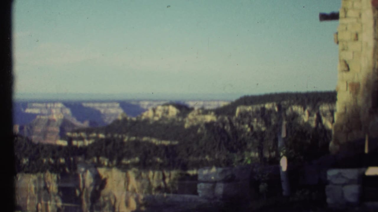 Canyon landscape framed by stone structures and a dark vertical edge.