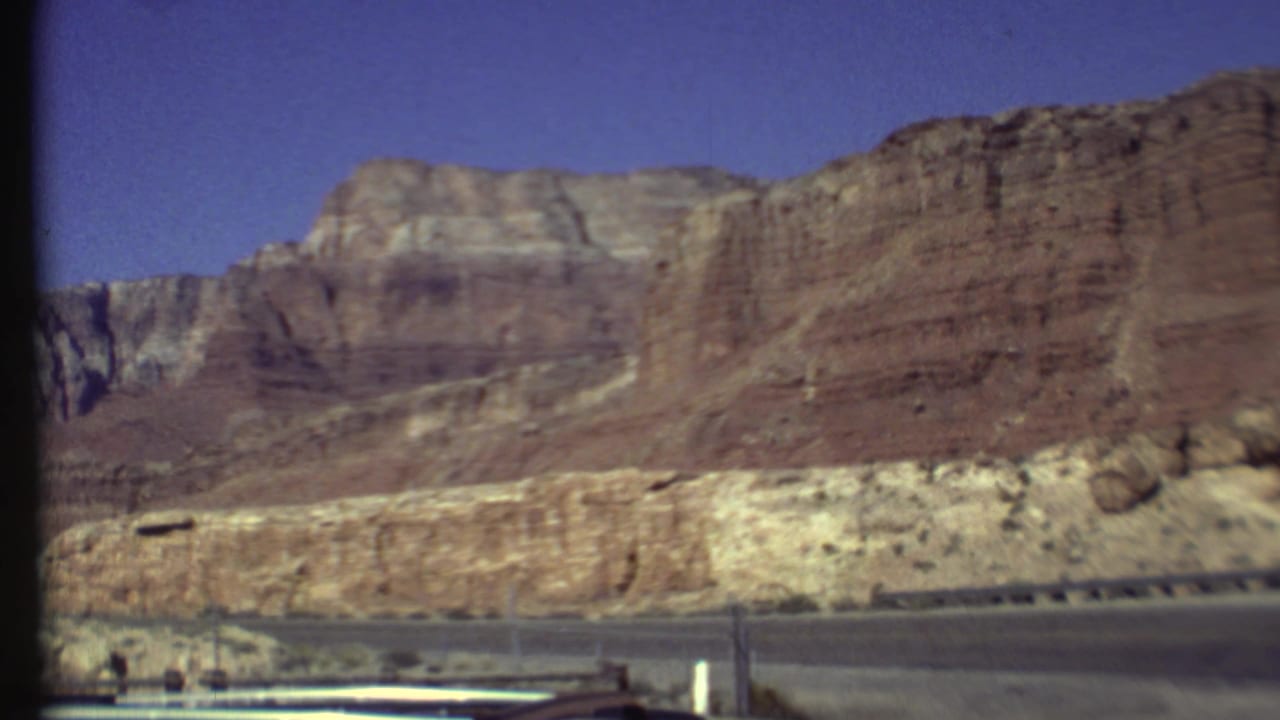 Canyon wall and roadside barrier with open blue sky above.