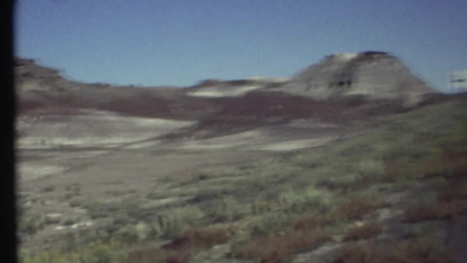 Vintage 8mm roadside view of scrub desert and rounded rock formations near Grand Canyon, Arizona, during a 1972 trip.