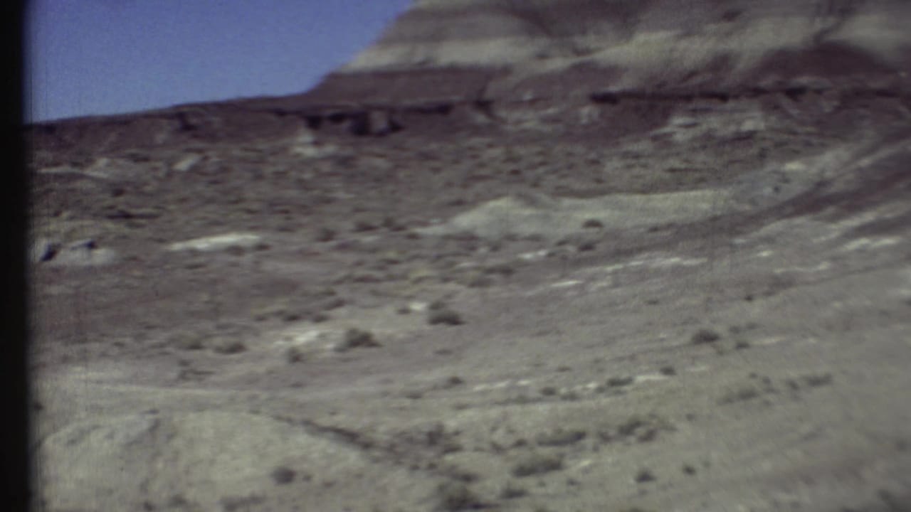 Dry grey-brown hills and scrubland beneath a blue sky.