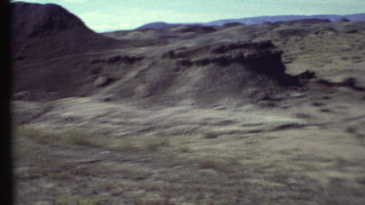 Dark eroded ridge and open scrubland across a dry desert landscape.