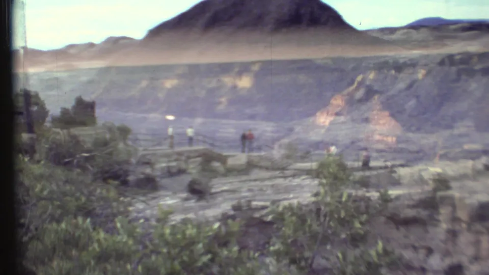 1972 Grand Canyon overlook scene with distant visitors, a path or railing, vegetation, and broad canyon walls in view.