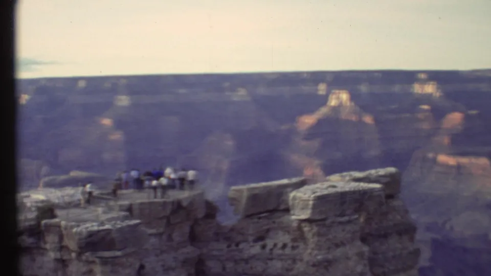 1972 8mm view of tourists gathered on a Grand Canyon overlook above distant layered rock formations.