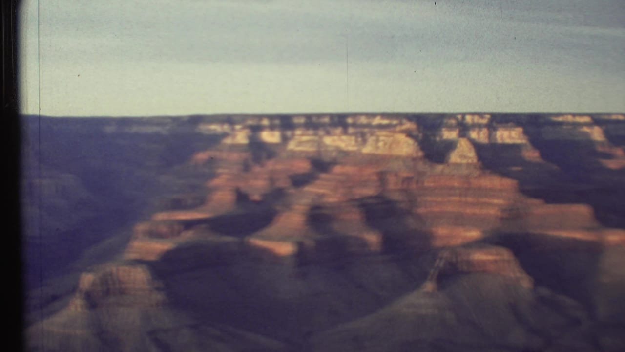 Soft 8mm view of Grand Canyon cliffs beneath a pale sky.