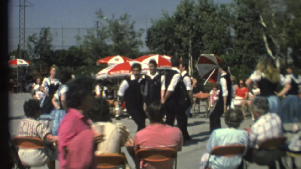 Final 1972 Grand Canyon frame with folk dancers in dark vests and blue skirts regrouping before a seated outdoor audience.