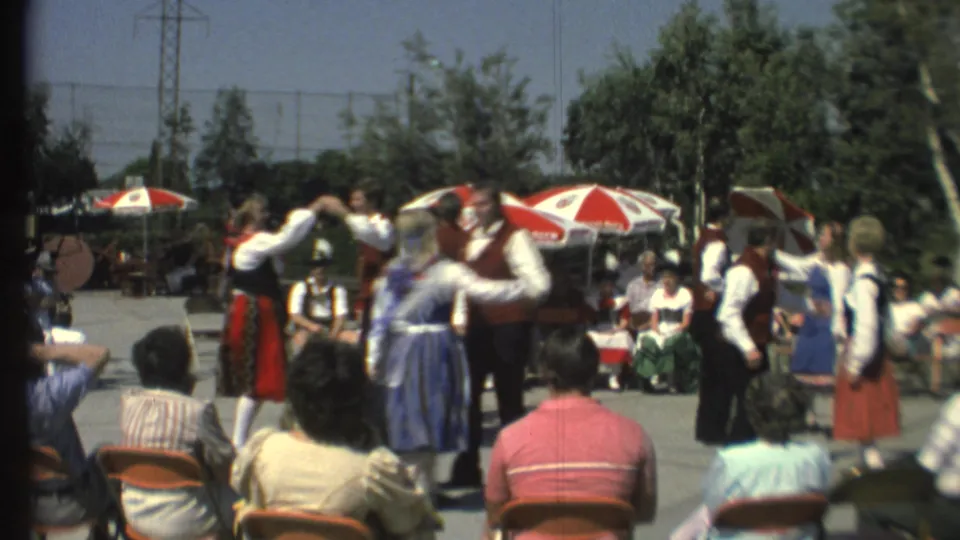 A handheld 8mm frame captures paired folk dancers turning in front of a seated crowd at an outdoor Grand Canyon festival setting.