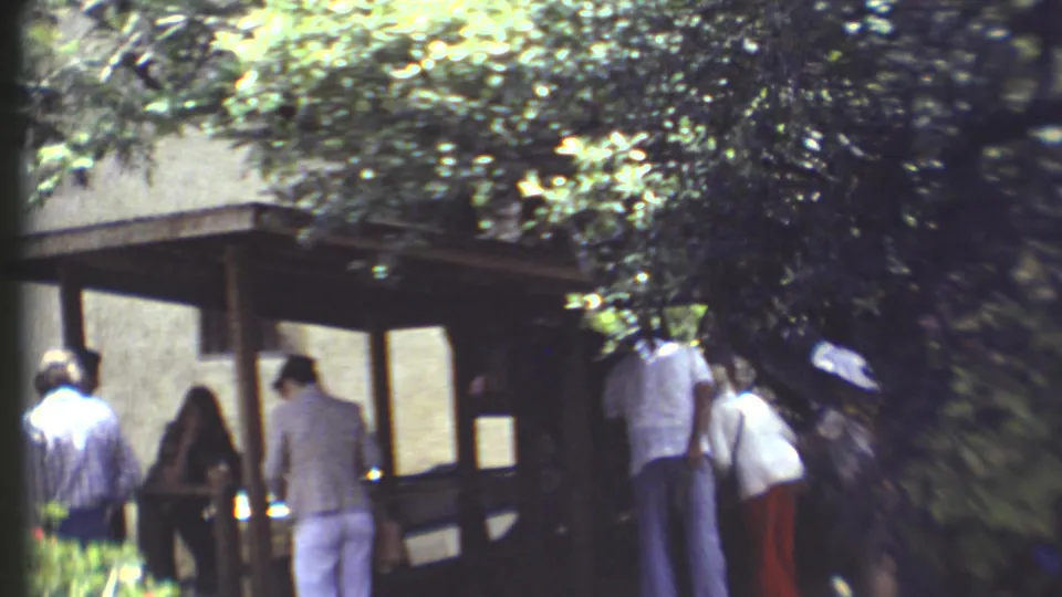 A group of visitors gathers near a small covered structure under trees in the 1972 Grand Canyon home-movie clip.