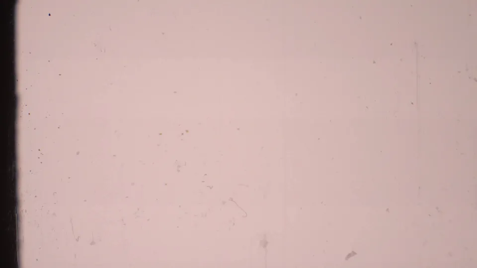 Pink-tinted 8mm leader frame showing dust, scratches, and subtle vertical film marks.