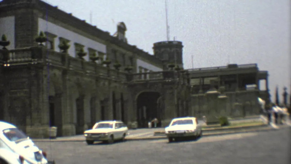 1973 Mexico City street view of a historic stone building with an arched entry, tower, pedestrians, and period cars.