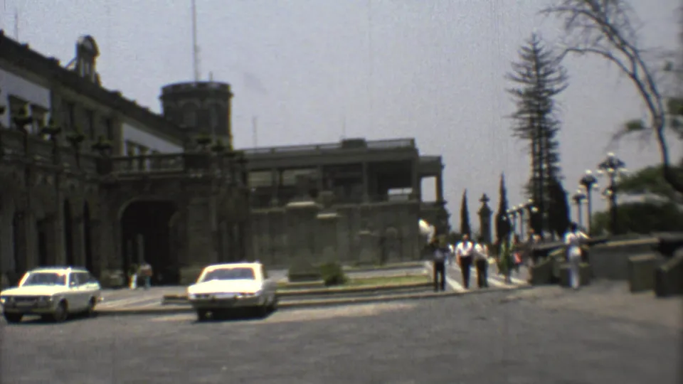 Mexico City street scene from 1973 showing a historic building exterior, cars, pedestrians near the walkway, and trees at the edge of frame.