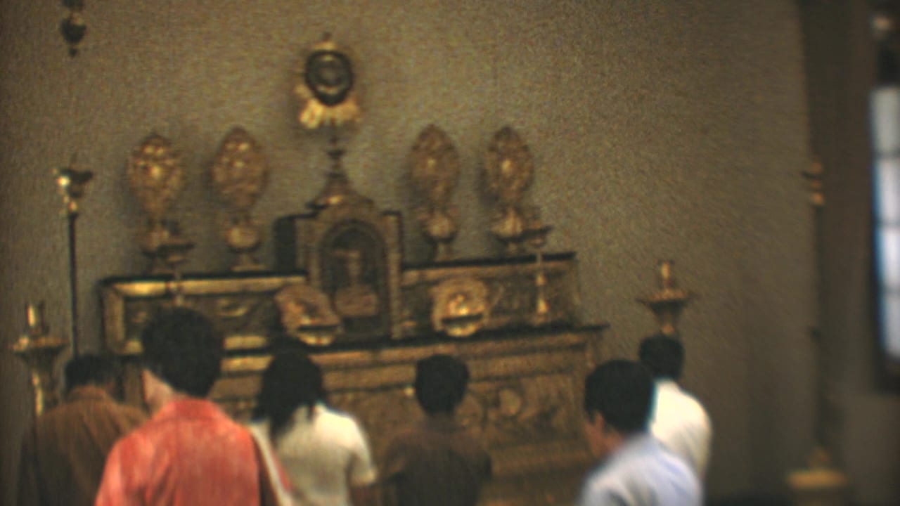 People gather near a gilded altar inside a church.