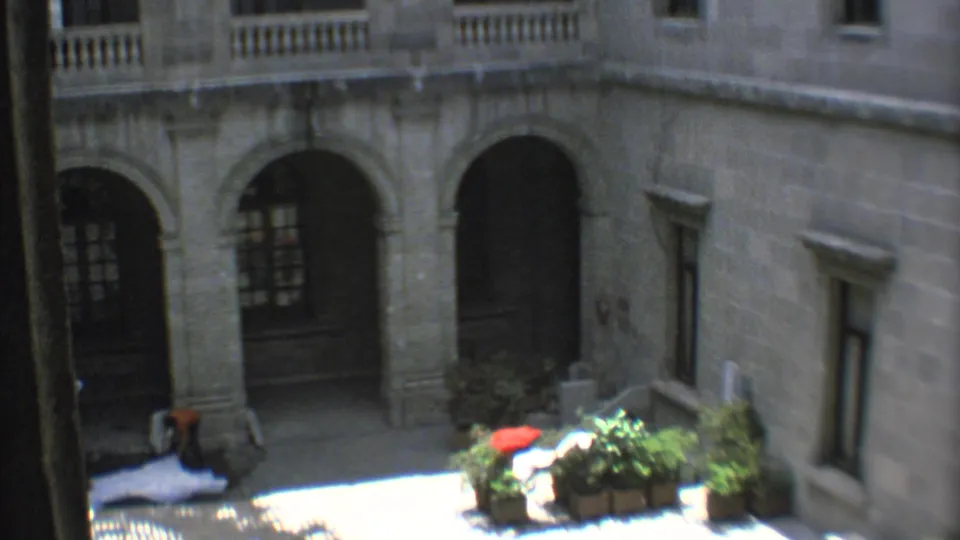 1973 Mexico City courtyard view with arched stone architecture, shadowed doorways, potted plants, and strong midday light.