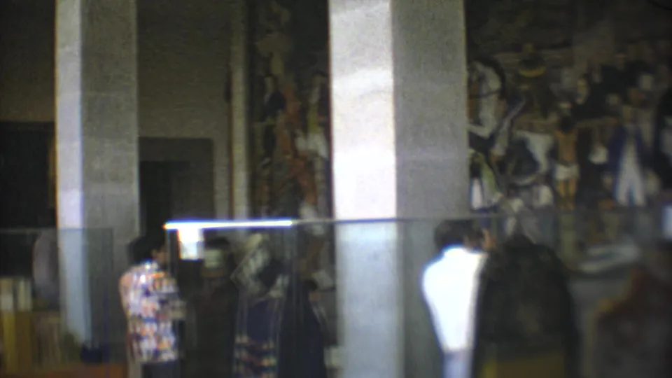 A 1973 Mexico City gallery view shows visitors facing a large mural behind reflective glass and columns.