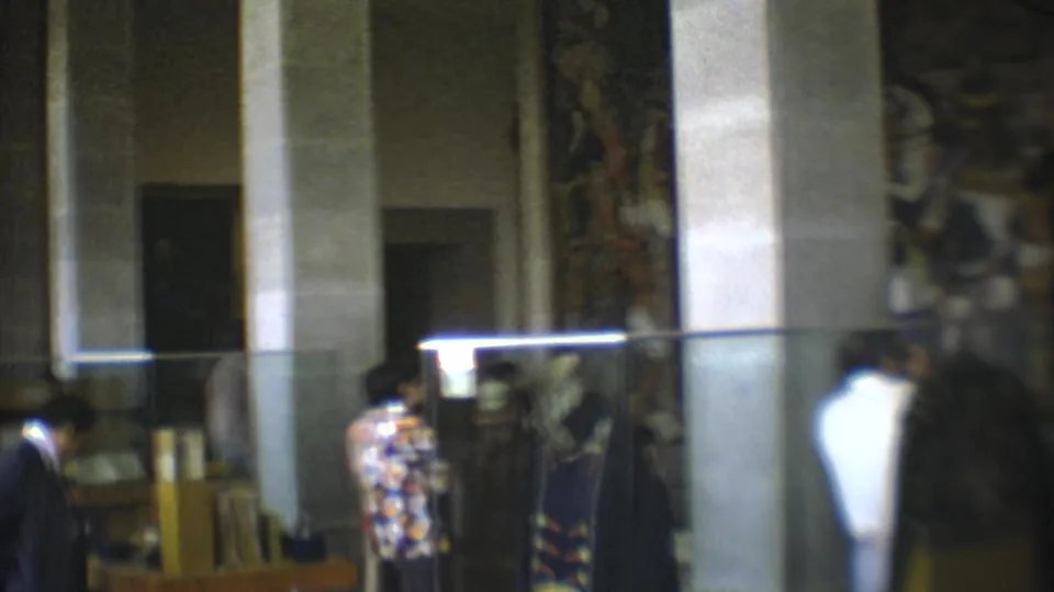 1973 Mexico City museum visitors view glass-covered displays in a columned interior with a mural in the background.