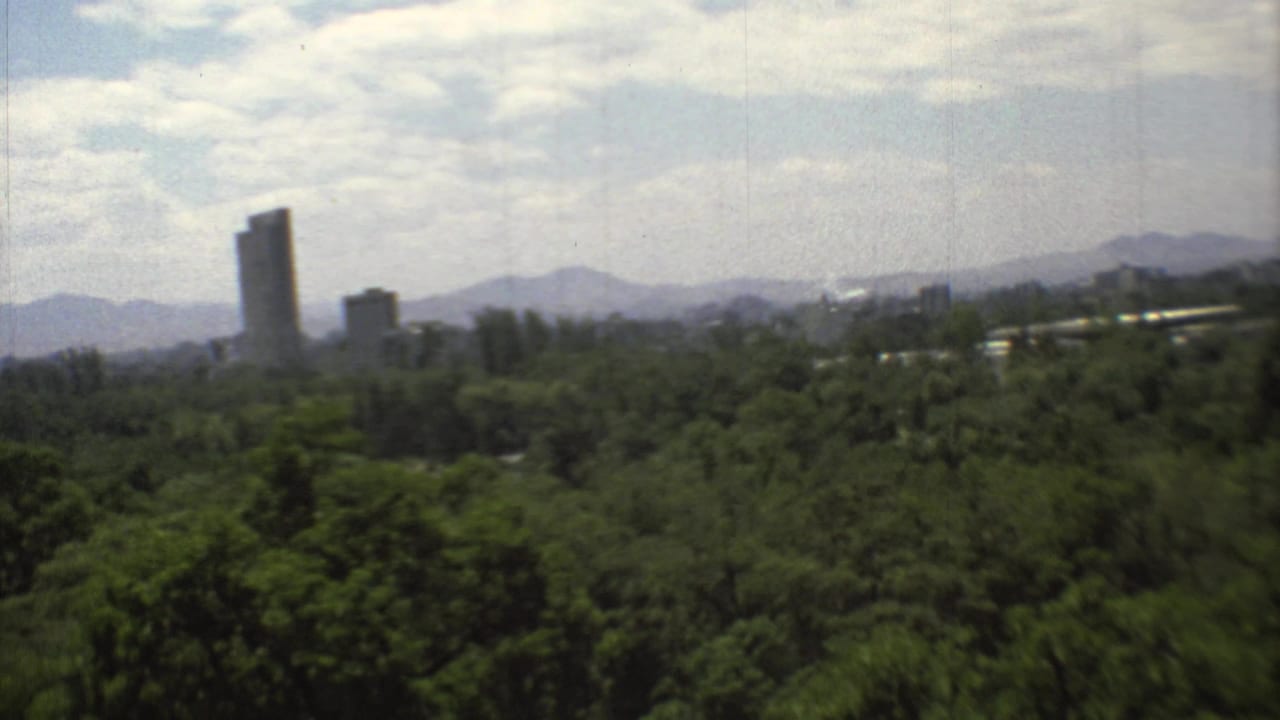 The final frame centers a tall distant tower above trees, with Mexico City buildings and mountains under a bright cloudy sky.