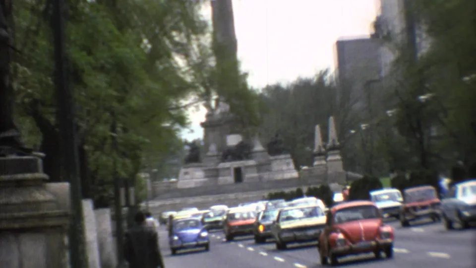 Mexico City avenue in 1973 with the monument set back beyond rows of classic cars and roadside trees.