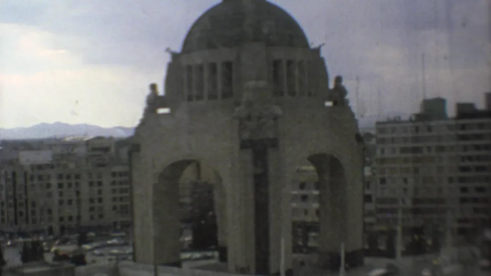 1973 Mexico City view of the Monument to the Mexican Revolution with surrounding buildings, pale sky, and mountains in the distance.