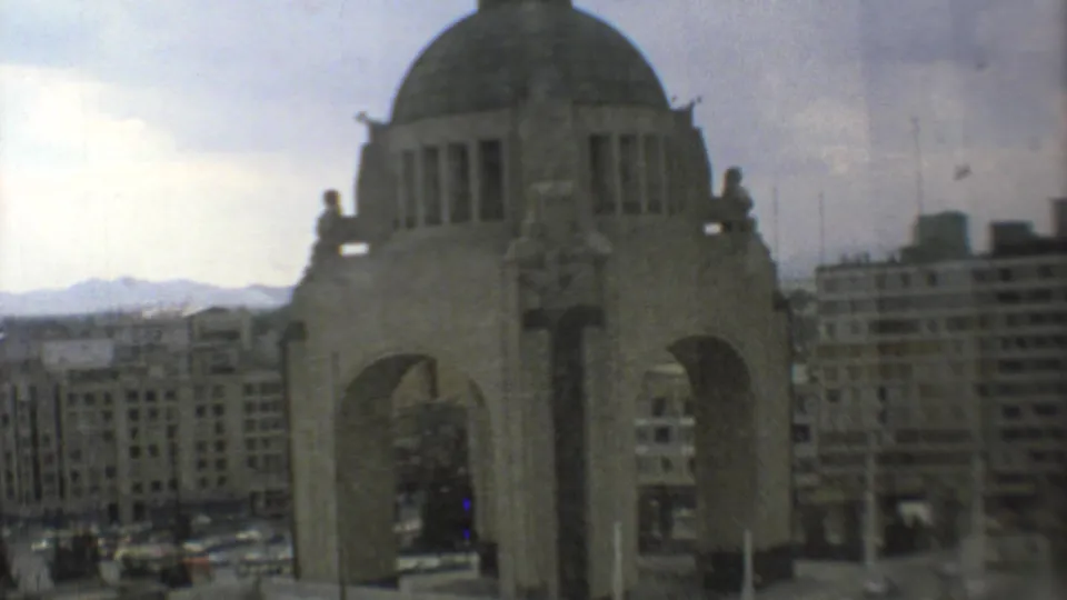 The Monument to the Mexican Revolution appears in a faded 8mm view with Mexico City buildings, mountains, and window reflections visible.