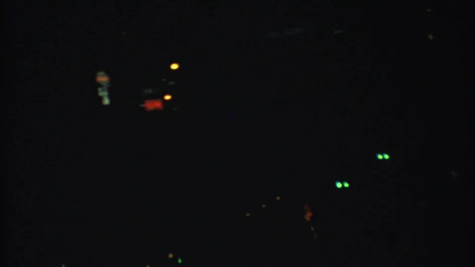 The clip ends on a very dark frame with small green, orange, and red lights, suggesting a nighttime shift or underexposed scene.