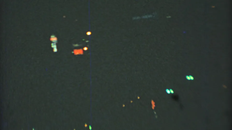 1973 Mexico City 8mm night-driving frame with scattered neon-like lights glowing through heavy darkness and grain.