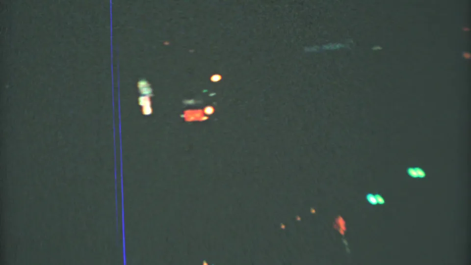 Mexico City night-driving frame from 1973, showing dim street movement, green lights, and a small red sign softened by 8mm grain.