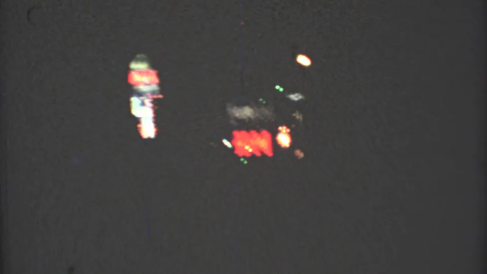 Late clip frame from the 1973 Mexico City night drive, with red and green lights smeared by low-light 8mm motion.