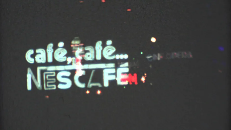 1973 Mexico City frame with a prominent cafe, cafe and Nescafe sign illuminated at night.