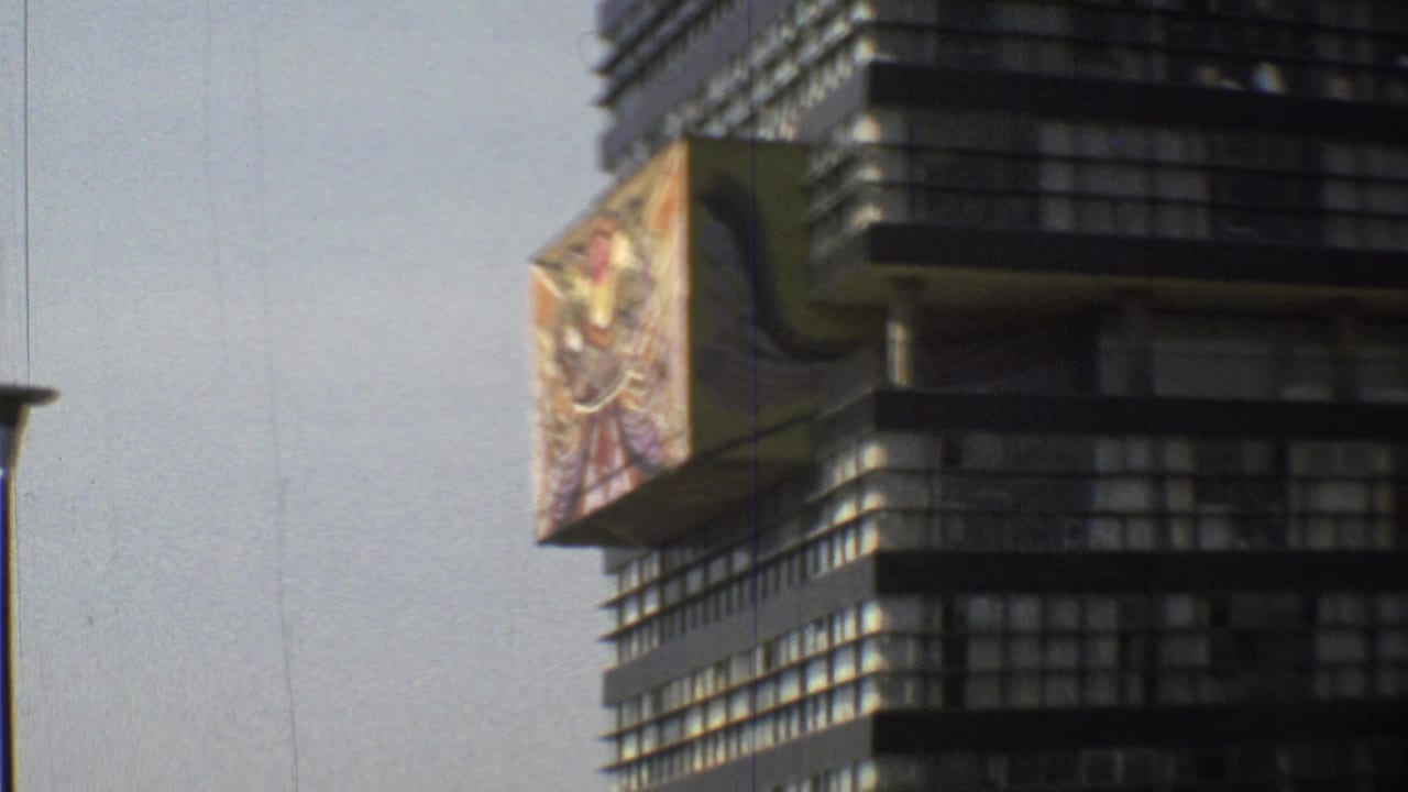1973 Mexico City street view of a dark modern building beside a large colorful mural panel, with greenery below.