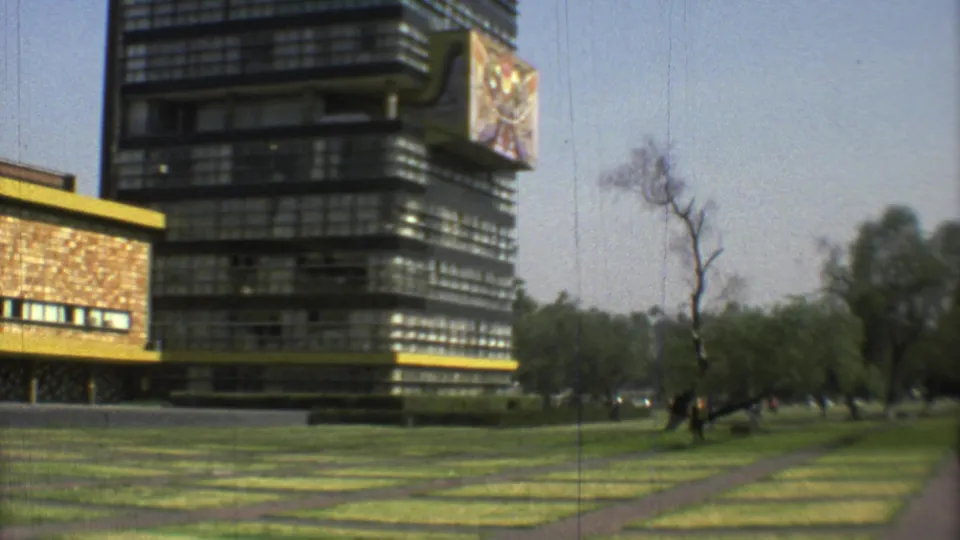 Mexico City park grounds in 1973, showing geometric lawn strips, paved paths, trees, and dark modernist building facades.