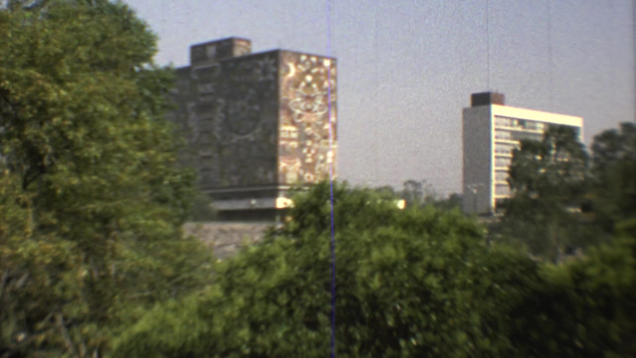 1973 Mexico City 8mm frame showing leafy park growth before a mosaic landmark and a white high-rise tower.