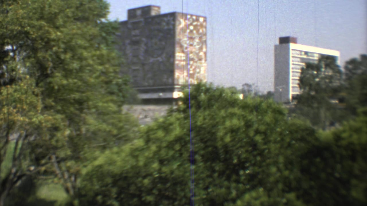 A wider 1973 Mexico City 8mm frame shows greenery in the foreground with a mural-like high-rise surface and pale modern building beyond.