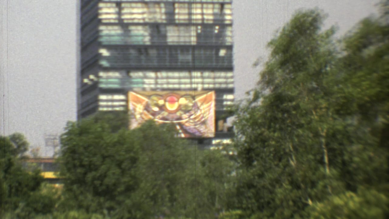 1973 Mexico City 8mm frame showing a colorful abstract banner on a modern high-rise, partly framed by trees.
