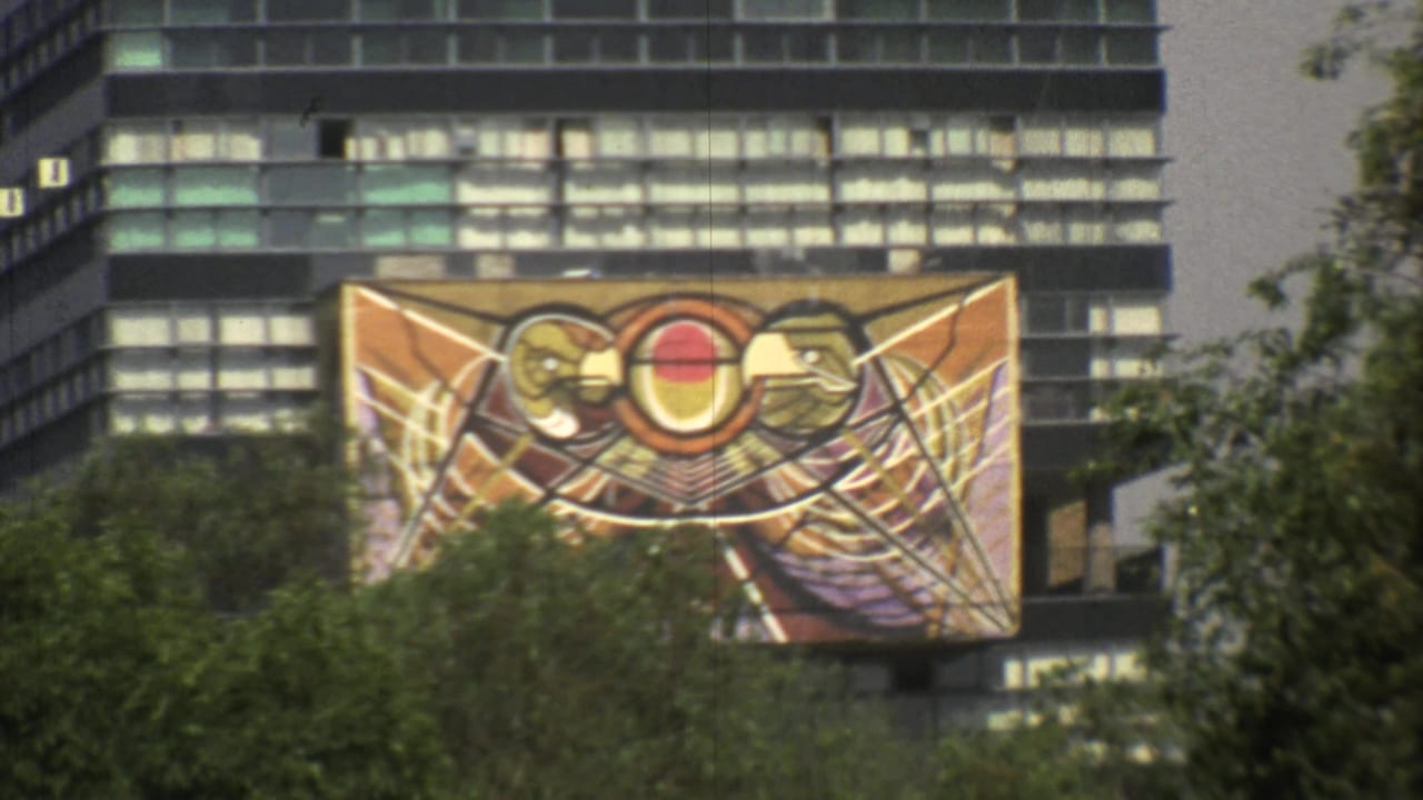 The camera frames a warm-toned abstract banner mounted against a Mexico City high-rise facade in 1973 footage.