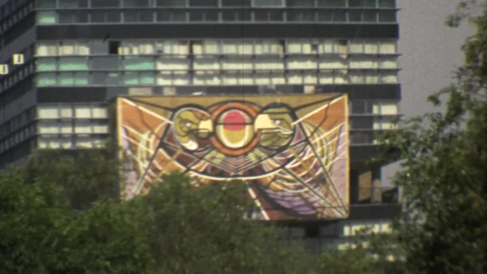 The camera frames a warm-toned abstract banner mounted against a Mexico City high-rise facade in 1973 footage.