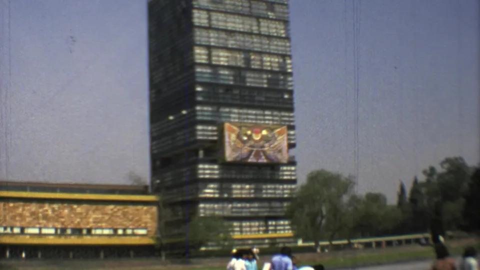 1973 Mexico City 8mm frame showing a tall modernist glass building with a large mural and pedestrians near a sunlit urban edge.